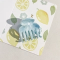Gros plan d'une pince à cheveux marbrée bleue en acétate sur fond de motifs citron - Bleu Lac 4cm 7 Dents
