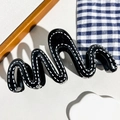 Dettaglio della pinza per capelli a onde in resina nera con motivo a cucitura bianca - Stile a Onda Nero