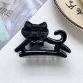 Detailansicht einer schwarzen Katzen-Haarklammer auf weißem Leder-Hintergrund - Glänzendes Schwarz