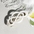 Dettaglio del fermaglio per capelli a infinito in resina crema su base bianca elegante - Beige