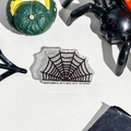 Detail of silver glitter spider web hair claw clip among Halloween festive decorations - Spider Web