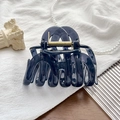 Detailed view of dark blue resin hair claw clip with golden metal spring on white texture - UV Transparent Navy Blue