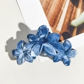 Gros plan d'une pince à cheveux bleue à texture marbrée avec un design floral élégant - Aigue-marine