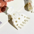Dettaglio del fermaglio per capelli bianco crema effetto marmo con motivi traforati - Beige
