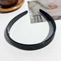 Dettaglio del cerchietto nero a tre strati antiscivolo con dentini su fondo bianco - Cerchietto Largo In PC A Righe / Nero Lucido