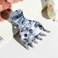 Dettaglio del fermaglio per capelli marmorizzato con design traforato su un libro - Grigio & Nero