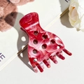 Dettaglio della pinza per capelli in acetato marmorizzato rosso e bianco con foro circolare - Borgogna