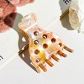 Close-up detail of marble textured acetate hair claw clip with stylish circular cutouts - Orange