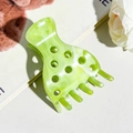 Macro detail of marble green strawberry hair claw clip with stylish cutout design - Cyan Green