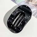 Vista dettagliata di una pinza per capelli ovale nera a pois bianchi su superficie ruvida - Nero Lucido Ovale / Nero Ovale a Pois (9.5cm)