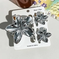 Détail d'un lot de 3 pinces à cheveux fleurs en métal argenté sur carte de présentation - Ensemble 3 Pièces Frangipanier / Aiguille en argent