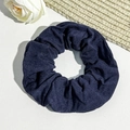 Detail of navy blue textured fabric scrunchie with elegant pleats on white leather - Navy Blue