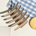 Detailed view of a light brown glossy hair claw clip on a stylish table setting - Matte Nude