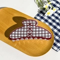 Close-up of retro checkered hair claw clip with red cross motifs on wooden tray - Square Tip Black Red Grid Bowtie (10.5cm)