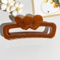 Detail view of a caramel brown rectangular hair claw clip with double heart cutouts - Orange Red