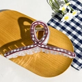 Close-up of a large checkered hair claw clip with a red and black pattern on a wooden tray - Cross Black Red Grid Bowtie (12.5cm)