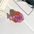 Gros plan d'une pince à cheveux en forme de poisson rose avec une finition brillante - PVC / Poisson rose orange