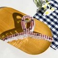 Detail of red checkered hair claw clip with bow pattern on wooden tray and daisy background - Cross Red Plaid Bow (12.5cm)