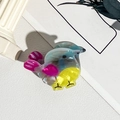 Gros plan d'une pince a cheveux baleine montrant la texture marbree en acetate - PVC / Poussin Bleu Et Jaune