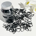 Primer plano de gomas negras elásticas en un frasco de plástico transparente con tapa - Negro