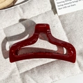 Close-up of translucent burgundy fish-tail hair claw with minimalist hollow geometric design - Transparent Wine Red