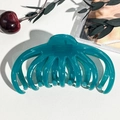 Dettaglio di una grande pinza per capelli a polpo blu petrolio per capelli folti su pelle - Blu Pavone Trasparente
