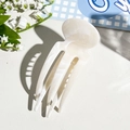 Detail van witte marmeren hars haarkam met vier tanden op wit lederen achtergrond - Beige