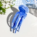 Detail van de vierpolige haarklem van acetaat met een blauw-wit marmerpatroon op de tafel - Hemelsblauw