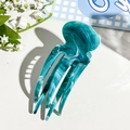 Detail view of jellyfish-shaped green marble hair claw clip on white leather background - Lake Green