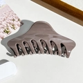 Detailansicht der glänzenden dunkelbraunen Haarklammer auf minimalistischem weißem Grund - Braun