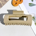 Detail of a large matte beige soft silicone hair claw clip on a textured white background - 10.5cm Milk Coffee