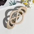 Detail of beige infinity knot hair clip showing the silver metal spring and smooth finish - Nude