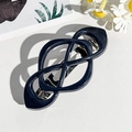 Detail of dark blue geometric knot hair clip with silver metal spring fastener on white leather - Sapphire Blue