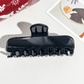 Draufsicht auf eine glänzend schwarze Haarklammer mit 10 Zähnen auf weißem Ledergrund - 11cm Rechteckig Schwarz Glänzend