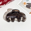 Detailed view of a dark brown translucent hair claw clip on a white leather surface - 9cm Handbag Style Transparent Dark Coffee