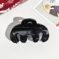 Close-up of black high-gloss hair claw clip with multi-tooth design on textured white surface - 9cm Handbag Style Black Glossy