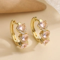 Macro shot of gold hoop earrings featuring three pink heart-shaped zircons and tiny diamonds - Pink