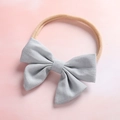 Gros plan détaillé d'un grand nœud gris argenté sur un bandeau pour bébé rose doux - Bleu