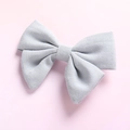 Detailed close-up of light blue linen hair bow clip showing fine fabric texture and craft - Blue