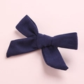 Detail showing the navy blue cotton bow hair clip texture on a pink background - Navy Blue