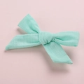 Close-up of mint green cotton bow hair clip with textured fabric on a pink background - Mint Green