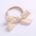 Detailed macro of soft cotton linen baby bow headband with white cross stitch embroidery - Beige