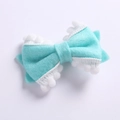 Détail d'un nœud à cheveux en feutre vert menthe avec bordure en pompons pour enfants - Bleu lac