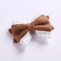 Détail d'un nœud papillon en feutre marron avec pompons blancs pour accessoires cheveux - Marron