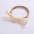 Gros plan d'un bandeau extensible en nylon pour bébé avec un nœud en velours beige doux - Beige