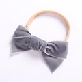 Nahaufnahme von weicher grauer Samtschleife und hautfarbenem Baby-Nylon Stirnband - Grau
