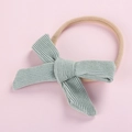 Close-up of mint green corduroy bow and soft nylon headband for newborn girls - Bean Green