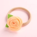 Detail van handgemaakte vilten roos op een zachte elastische nylon hoofdband voor baby's - Oranje