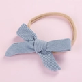 Close-up of light blue corduroy bow on nude elastic nylon headband for newborn infants - Light Blue