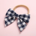 Détail d'un nœud à carreaux bleu foncé sur bandeau bébé beige en nylon souple - Pois Bleu Denim